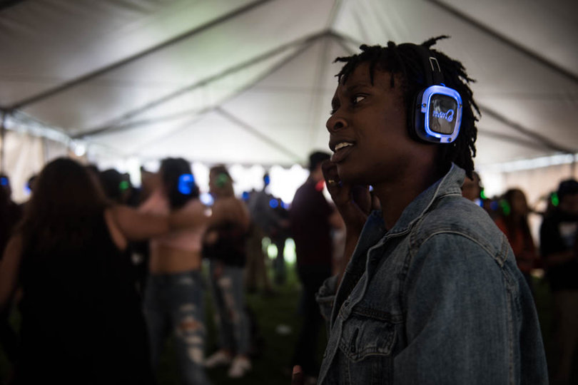 Naomi Nelson, a sophomore geography major, listens to the "Silent Events" concert in the tent to escape the rain.