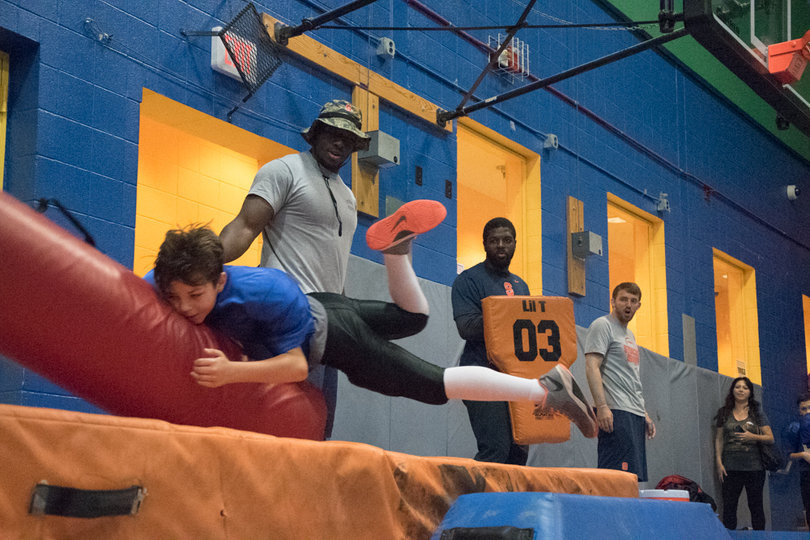 A player launches himself forward into a tackling dummy and onto a cushioned mat.