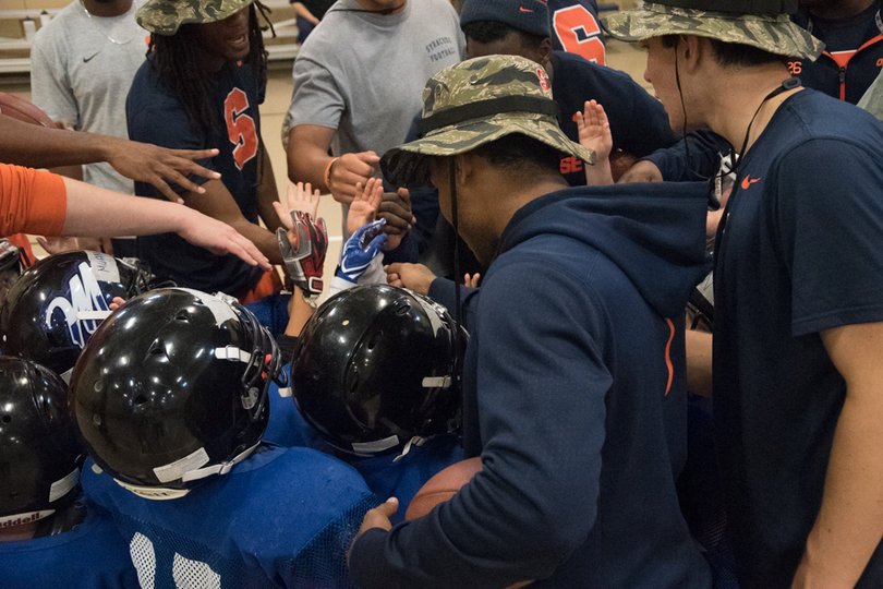 Syracuse players and clinic attendees put their hands in as they get pumped up.