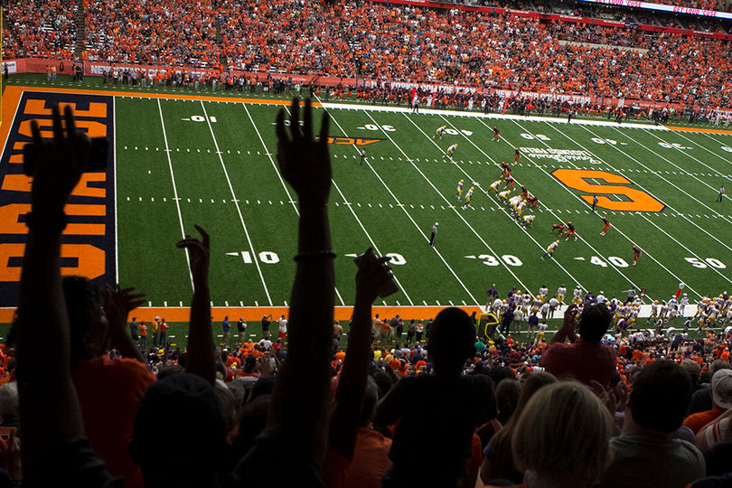 Fans raise their hands to cheer for the Cuse football team. 