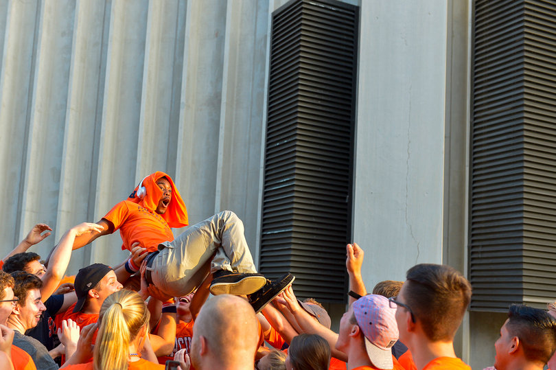 A fan gets hoisted above a sea of orange as a crowd forms in the parking lot of the Carrier Dome. 