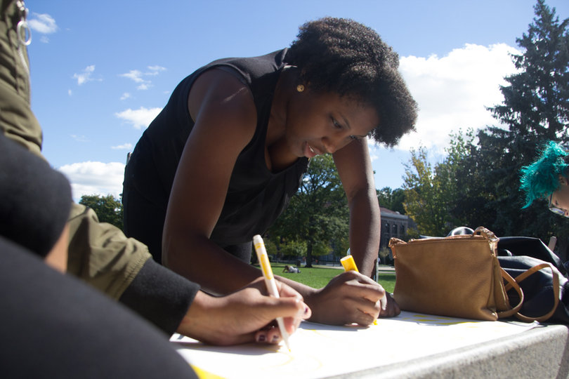 Diamond Miles, president of Syracuse University's chapter of the National Association for the Advancement of Colored People (NAACP), creates a poster before the march starts.