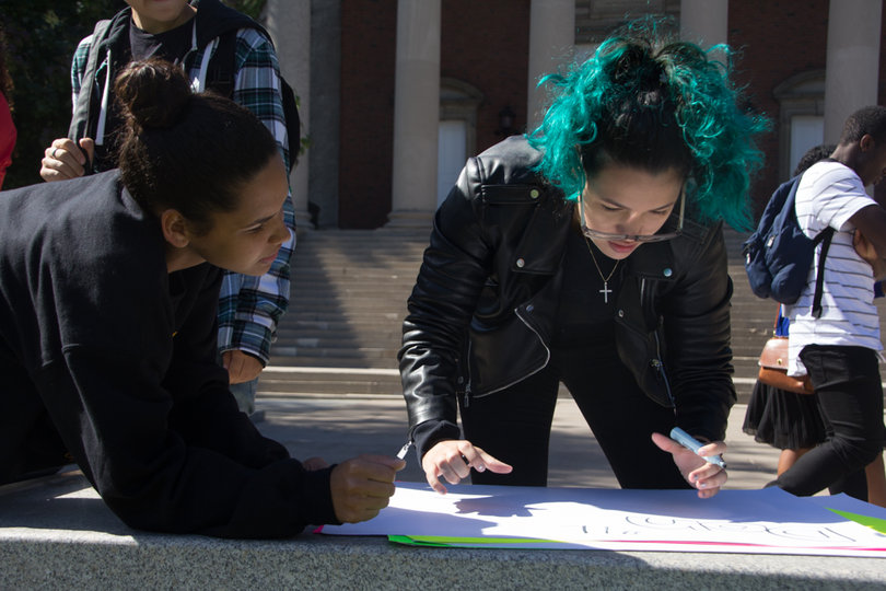Syracuse University students make posters before the beginning of the march on Saturday afternoon.