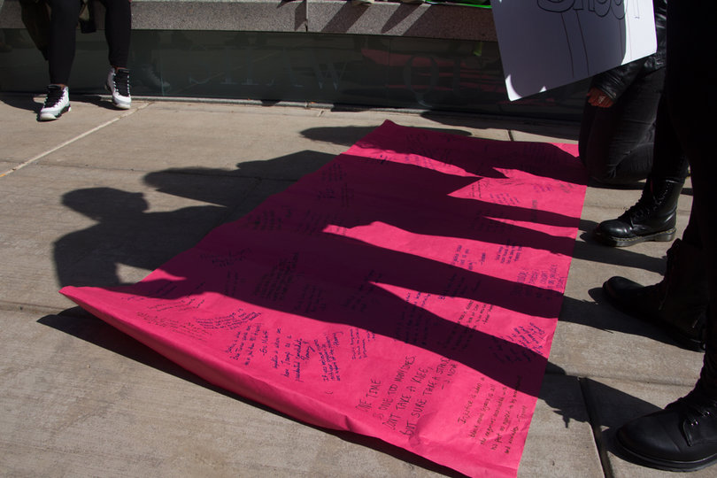 SU students stand over a signed "Am I Next" banner before the march against police brutality began on Saturday afternoon.