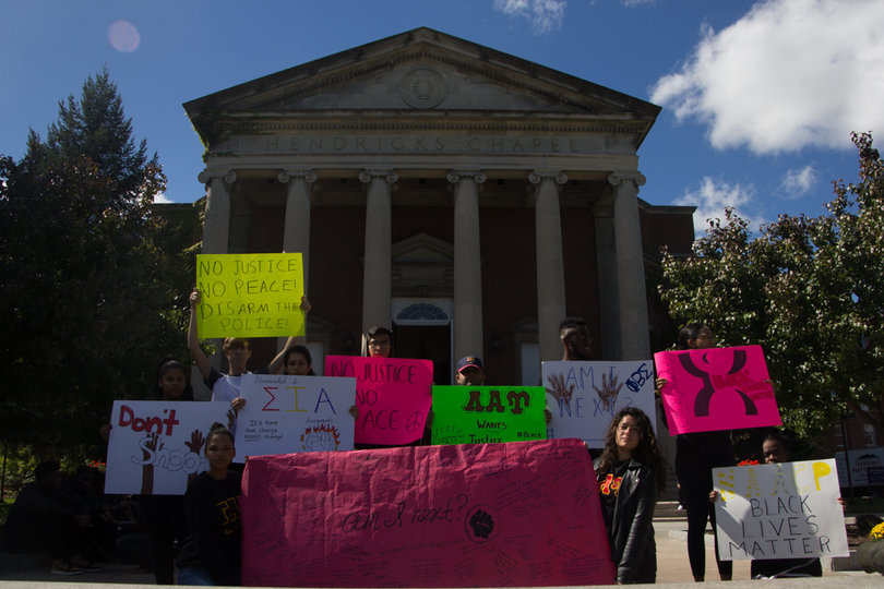 Students stand in front of Hendricks Chapel raising posters with messages against police brutality and in support of the Black Lives Matter movement.