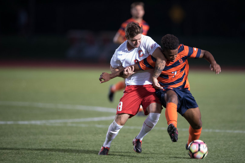 Orange midfielder Mo Adams uses his body and arm to shield Cornell's JJ Black from the ball.