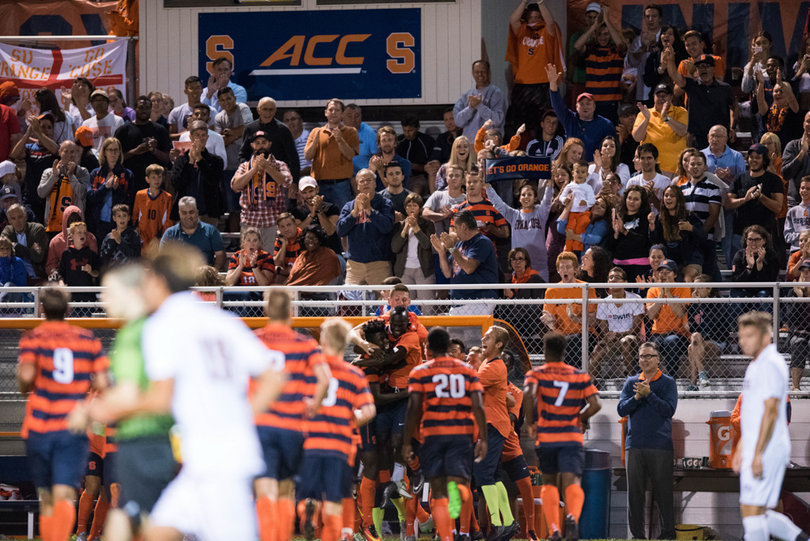 The Orange players celebrate a goal in front of their bench and fans. 