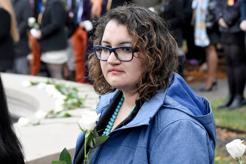 Nedda Sarshar holds a rose as others speak during the ceremony outside of the Hall of Languages.
