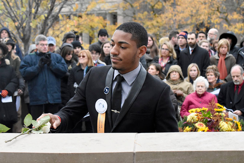 SU Remembrance Scholar Malik Evans places a rose.  
