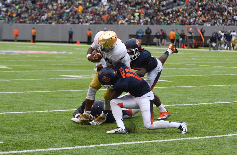 Orange cornerback Corey Winfield and two of his teammates make a tackle near the sideline.