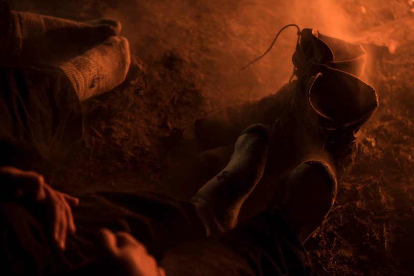 Smoke rises from the cold feet and shoes of water protectors as they warm their feet near the fire during a reprieve of fire hoses.