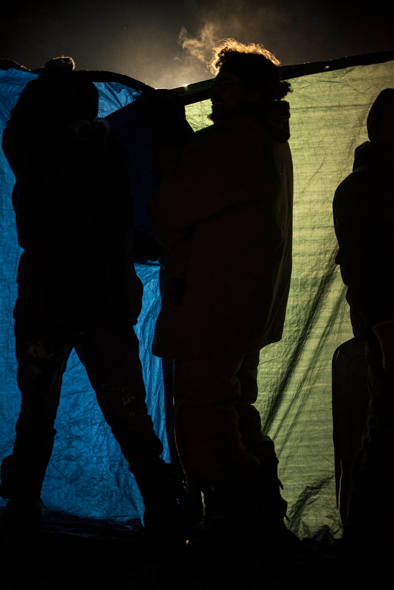 Water protectors near the barricade hold up tarps to protect other people from the water cannons that were causing hypothermia in the freezing cold temperatures.