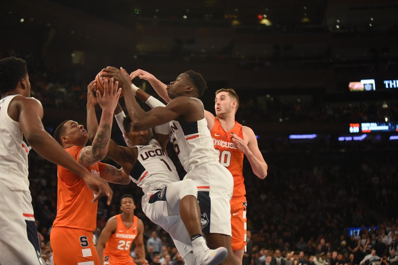 A cluster of Syracuse and UConn players fight for a ball.