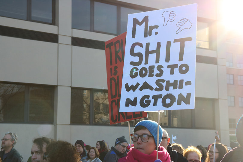 A woman carries a sign that says "Mr. sh*t goes to Washington." Signs at the rally carried both positive and negative messages.