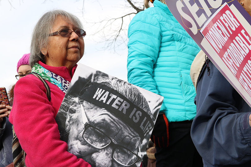 A woman holds a sign that says "Water is life," the same call activists from Standing Rock made during the Dakota Pipeline protests.