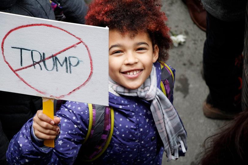 A child in the New York City sister march holds a small sign with Trump's name crossed out.