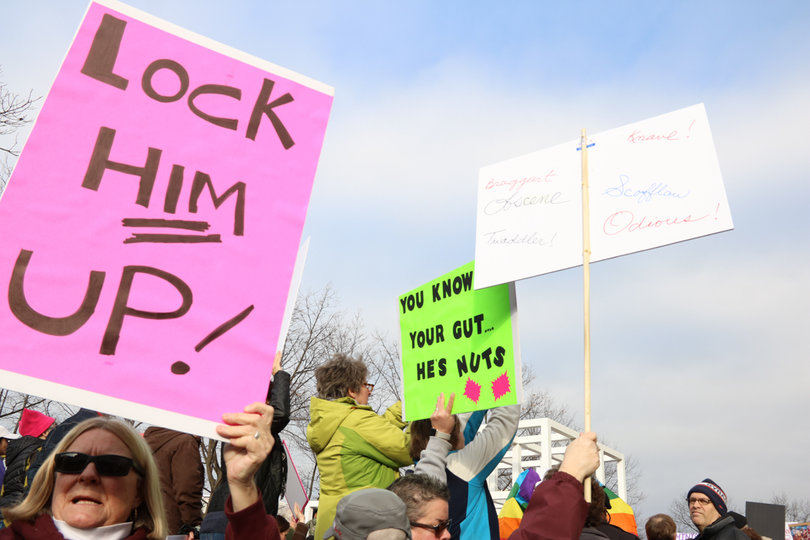 A Syracuse resident holds up a sign that says "Lock him up."