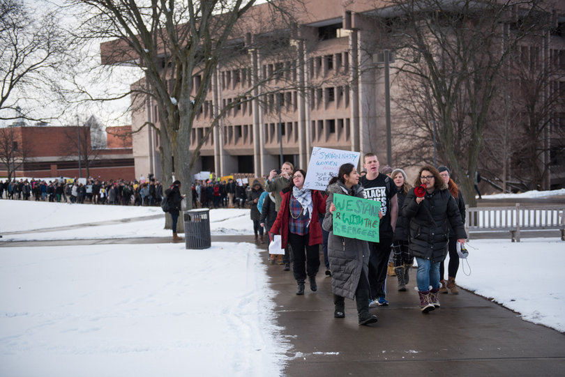 Arva Hassonjee (green sign) and Nedda Sarshar (megaphone) lead hundreds of students down Syracuse University's promenade on Thursday, Feb. 2, 2017 in a "Rally for Refugees" protest that they organized. The protest wound its way to the Life Sciences building for a sit-in and speakers afterwards. The protesters were rallying against President Trump's immigration policies he enacted since becoming president last month.