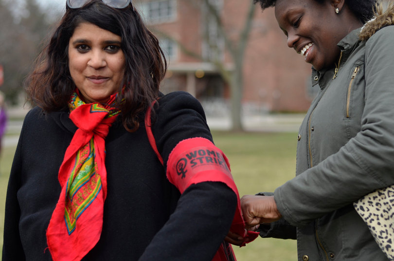Shanique Mothersill (right) helps 
Himika B. (left) tie her red "Women's Strike" armband on her arm.