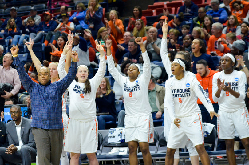 Players on Syracuse's bench celebrate the Orange's success while head coach Quentin Hillsman stands with his arms raised.