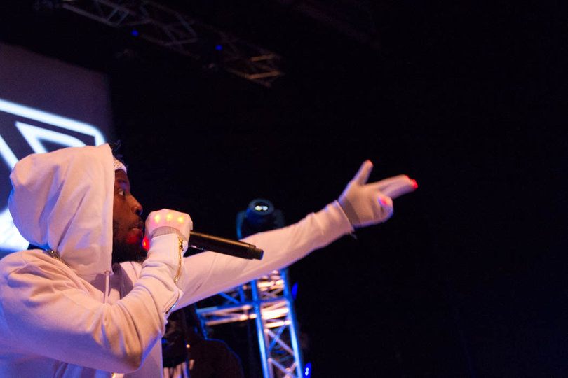 Henny Pica$o's all-white outfit stood out vibrantly under the colored lights.