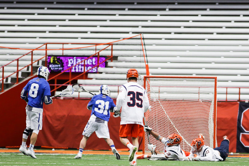 Tyson Bomberry tries to hold up his stick to prevent a goal while he and Molloy are on the ground. 