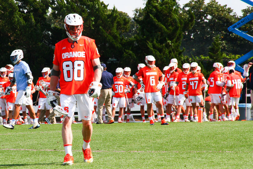 Andrew Helmer walks toward the field with his teammates in the background. 