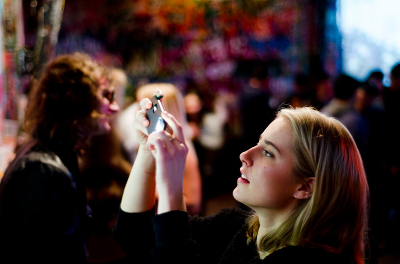 Claire Sorlie, a Syracuse University student, photographs the wall inside of Chuck's where she recently painted her name.