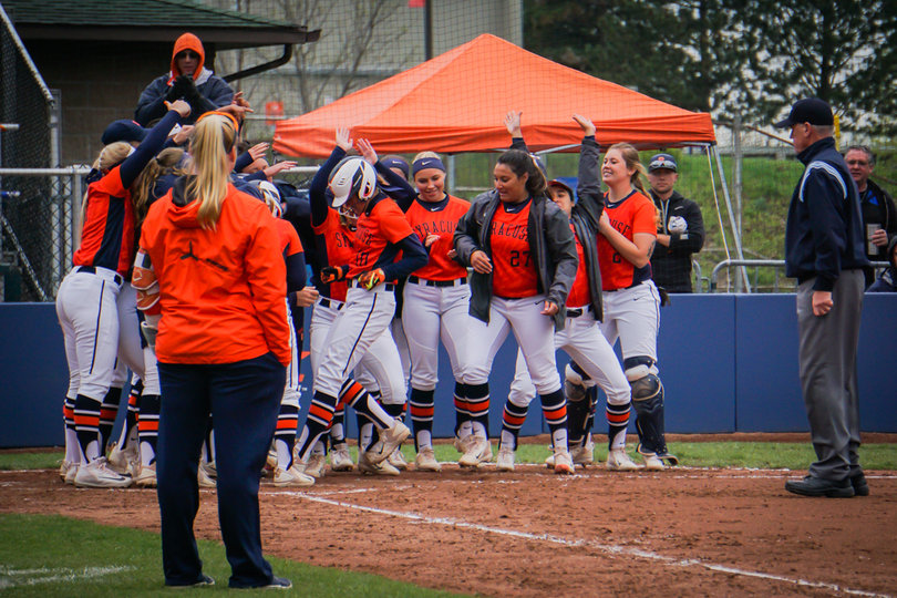 Hannah Dossett steps on home and is greeted by her teammates after hitting a home run. 