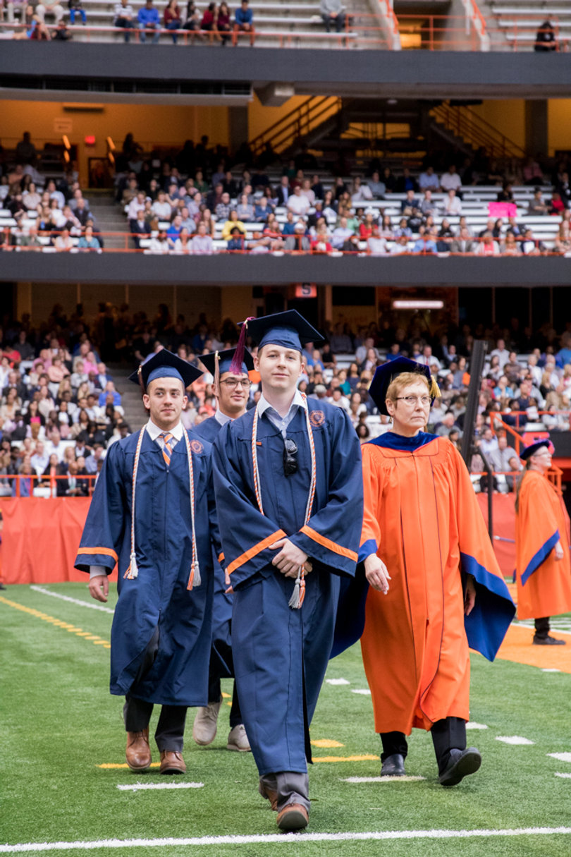 Students walk on to the Carrier Dome field. 