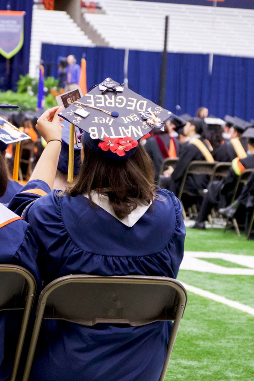 This student's cap says "Natty B got her degree." 