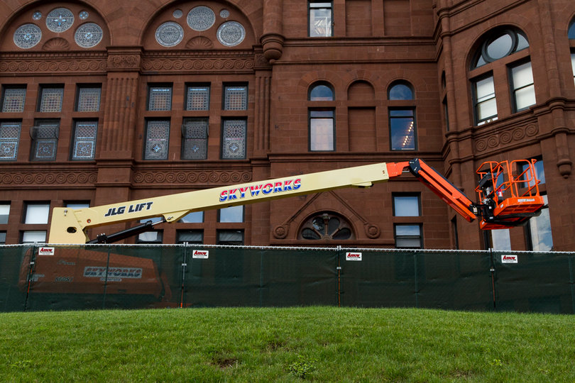 A piece of construction equipment is parked beside Crouse College as work continues on masonry restoration to the building's bell tower and building cupolas. Photo taken by July 11, 2017