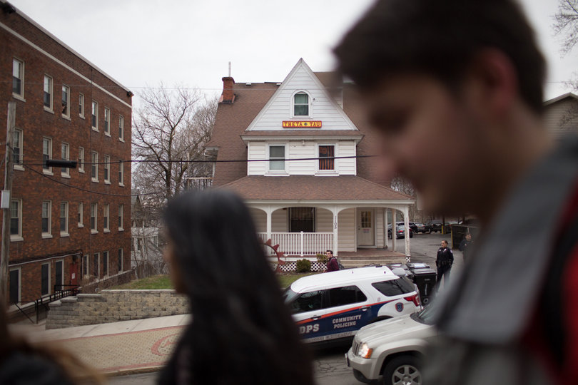 Demonstrators march past the Theta Tau house while Department of Public Safety officers stand outside. 