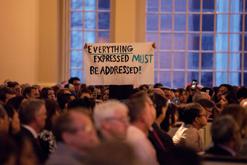 The “EVERYTHING EXPRESSED MUST BE ADDRESSED” sign is held up during the forum.