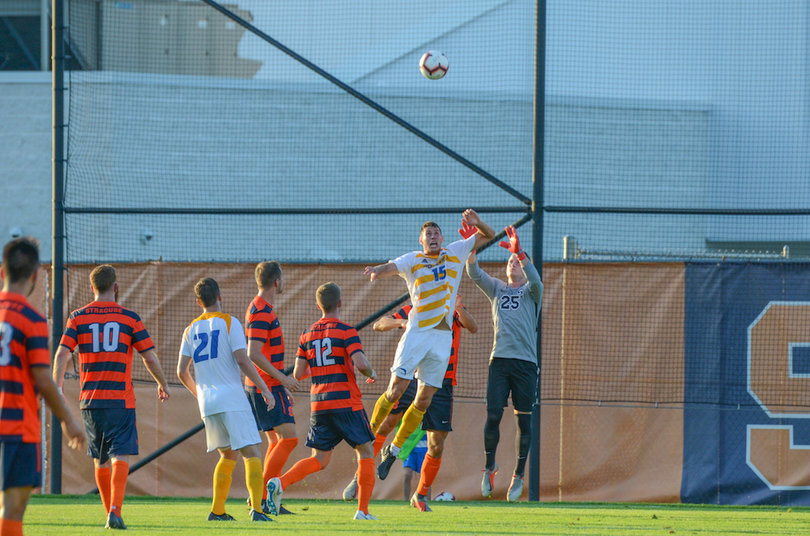 A Hofstra offensive player goes up high for a ball with Hilpert in pursuit from behind.