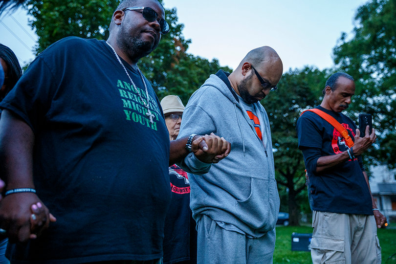 Community members bow their heads in prayer. 