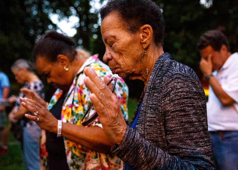 Community members join pastors and surviving family members, like Lawrence Moore Jr.'s family, in a moment of prayer to end violence in the city. 