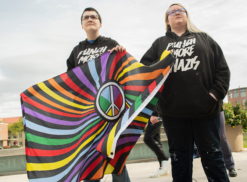 (Left to right): Molly, an SU graduate, and Kap, a local community member, hold a peace flag at the rally. 
