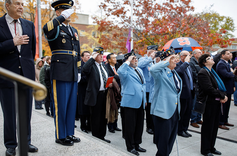 Korean War veterans salute as the flag is raised and a trumpeter plays "Reveille."