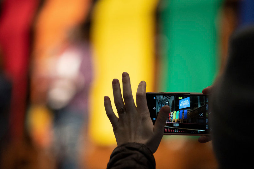A protester photographs a speaker as she shares her story at the microphone.
