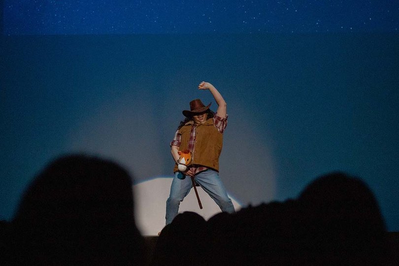 Bina Minute takes the stage in cowboy drag and performs to "Save a Horse, Ride a Cowboy" by Big and Rich. 