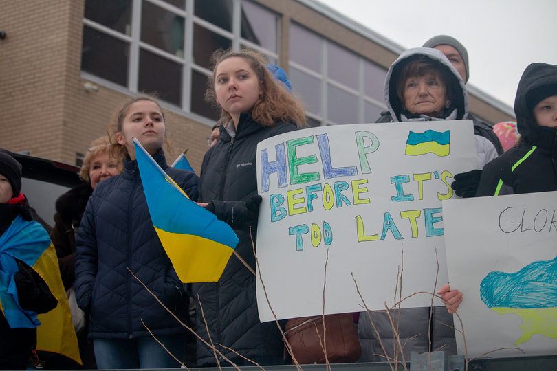 People hold posters and flags to raise awareness about the violence in Ukraine. 