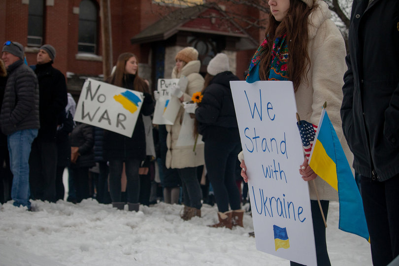 Signs reading "we stand with Ukraine" and "no war" fill the crowd outside the church.