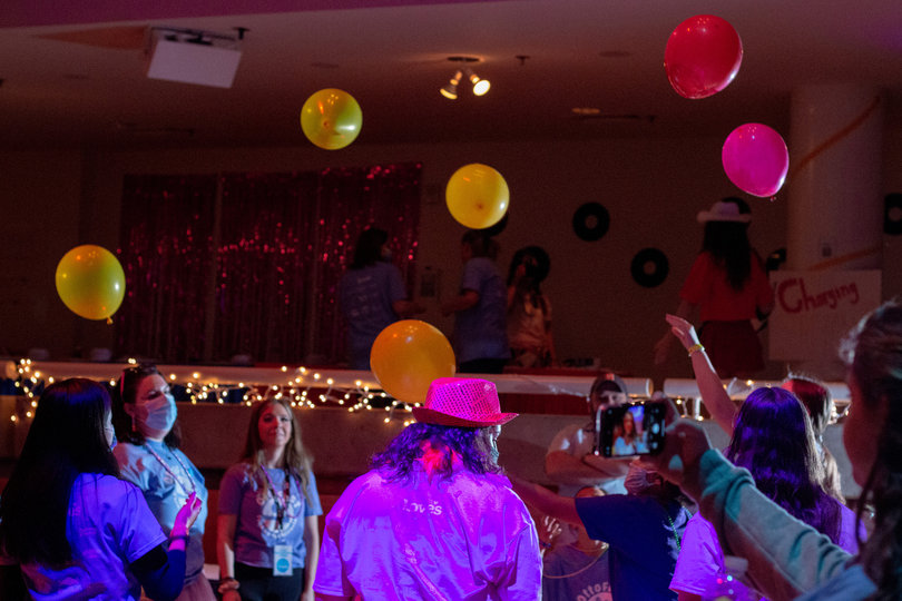 Balloon decorations are tossed around the auditorium while students dance and talk. 
