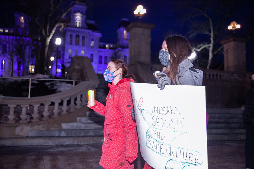 Two students march down the promenade with candles and signs sending messages about the culture that plays a role in sexual violence. 