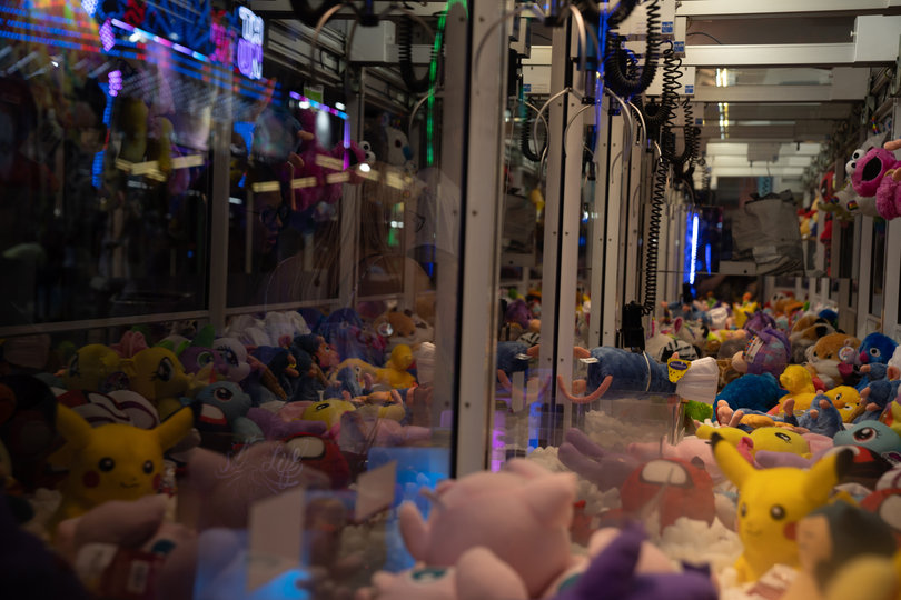 A fairgoer tries to pick up a stuffed Remy from "Ratatouille" from one of the New York State Fair's arcade claw machines.