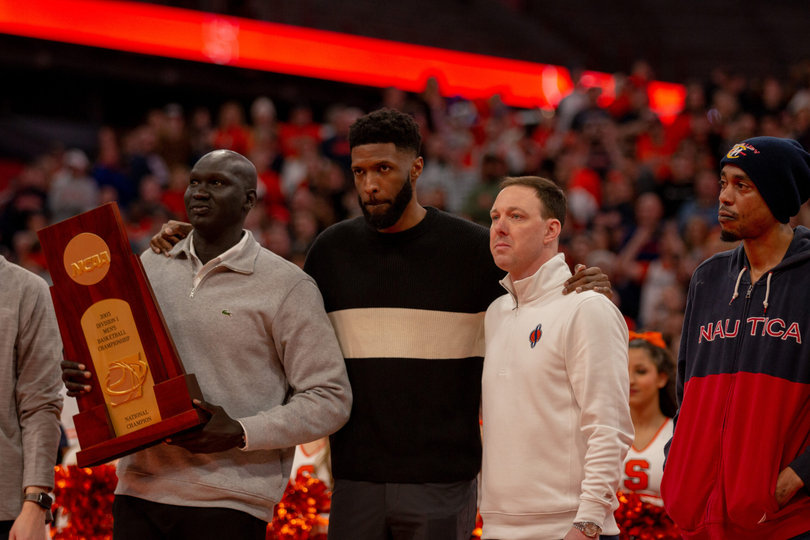 Former Syracuse basketball players Hakim Warrick, Gerry McNamara and Kueth Duany huddle together as their teammate Carmelo Anthony speaks. The three were part of former head coach Jim Boeheim’s first championship winning team in 2003. 