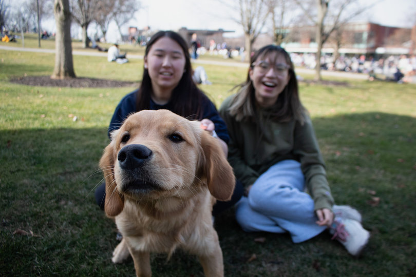 Two students smile with their dog.