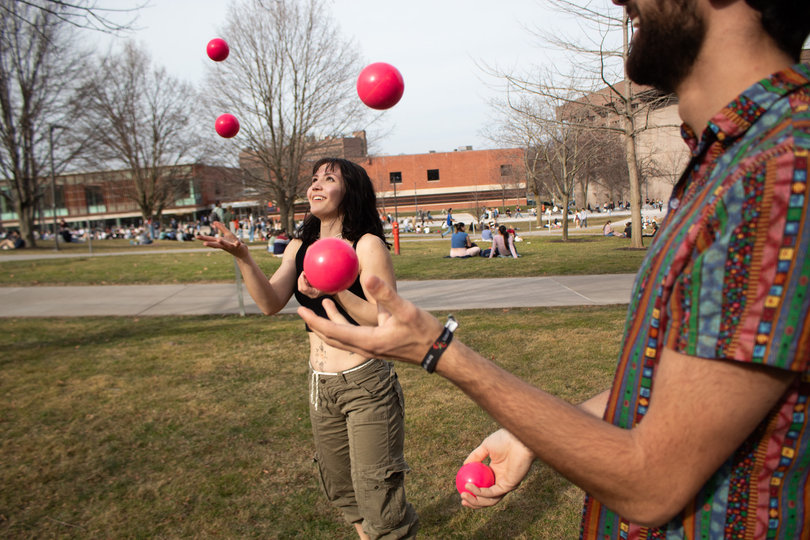 Two students juggle pink balls.