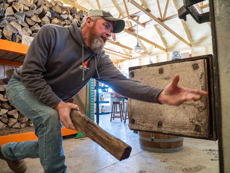 A man throwing wood into a furnace.